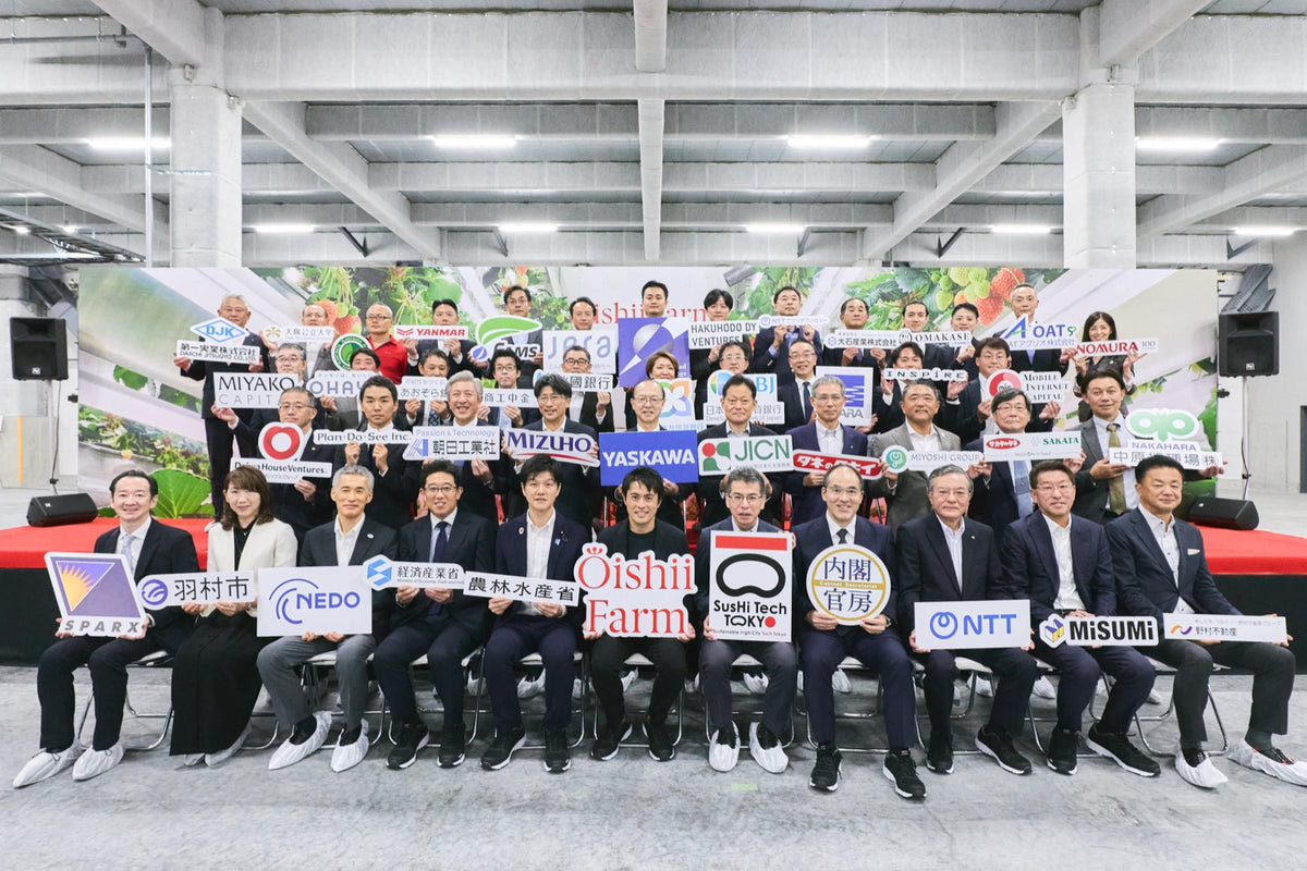 開所式で企業・団体のロゴを手に並ぶ参加者たち